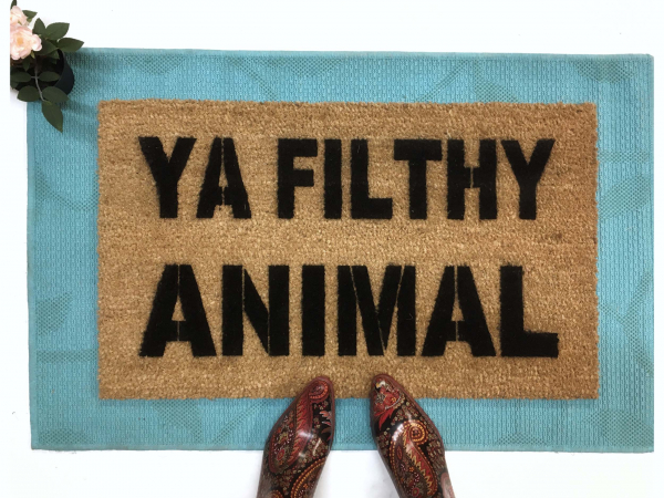 Ya Filthy Animal Home Alone doormat on top of a blue layering rug