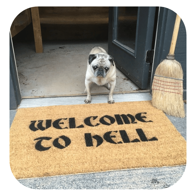 WELCOME TO HELL GOTHIC LETTERING coir doormat at spooky doorway with a fawn pug and witches broom