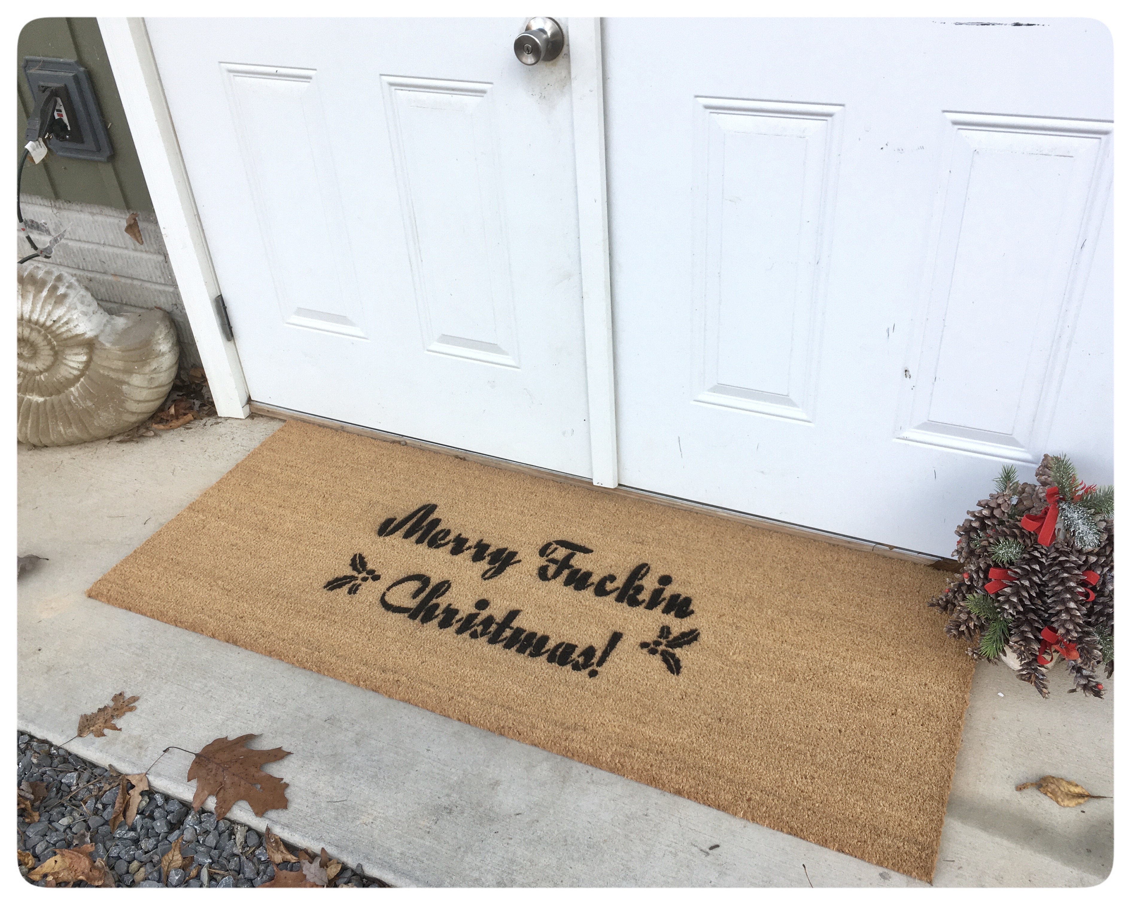 A sweary Christmas doormat on a front porch