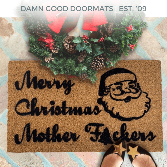 merry christmas mother fuckers doormat on a brick patio with christmas door wreath and woman in black flats with gold stars