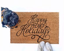 outdoor doormat reading happy holidays in script writing with a black pug puppy