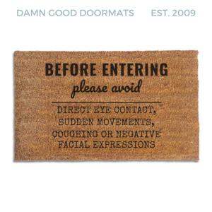 Coir doormat printed with Before Entering Please Avoid Direct Eye Contact, Sudden Movements, Coughing or Negative Facial Expressions in black house-rules lettering