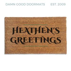 Coir doormat printed with Heathen's Greetings in black engraved capitals between thin green rules