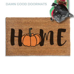Coir doormat printed with HOME in black brush lettering, with an orange pumpkin standing in for the O