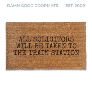 Coir doormat printed with All Solicitors Will Be Taken To The Train Station in black typewriter capitals