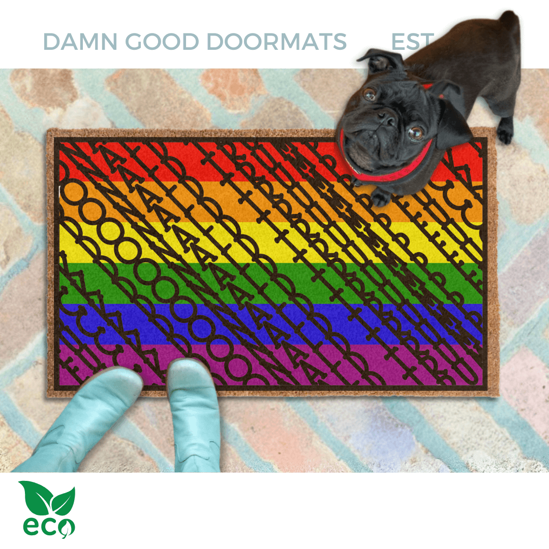 subtle fuck donald trump doormat in abstract contemporary design over gay pride rainbow flag. A pair of feet wearing baby blue boots stands with a black pug dog sitting on the floor next to them. 