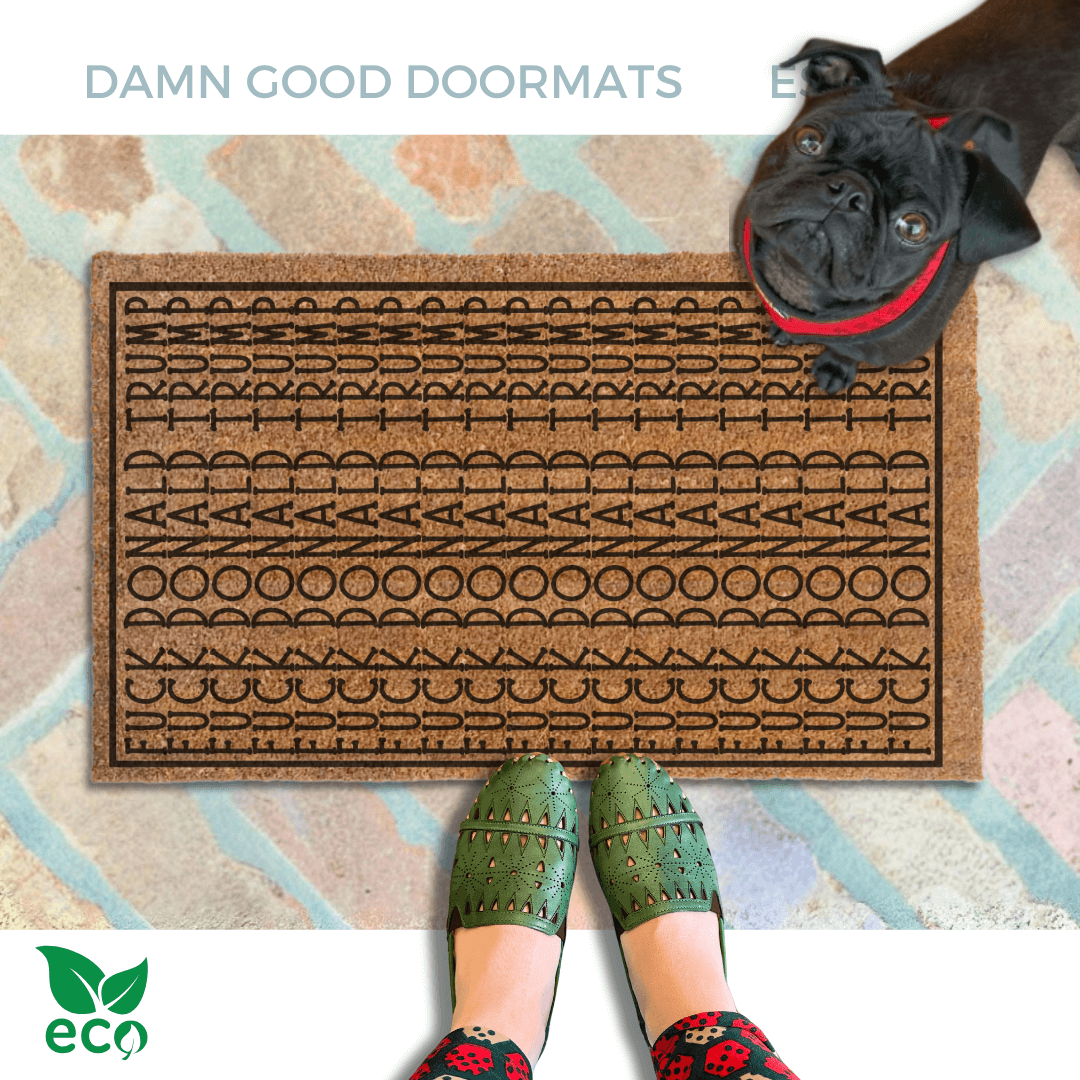 A pair of feet wearing green shoes stands on a subtle patterned FDT Fuck Donald Trump doormat