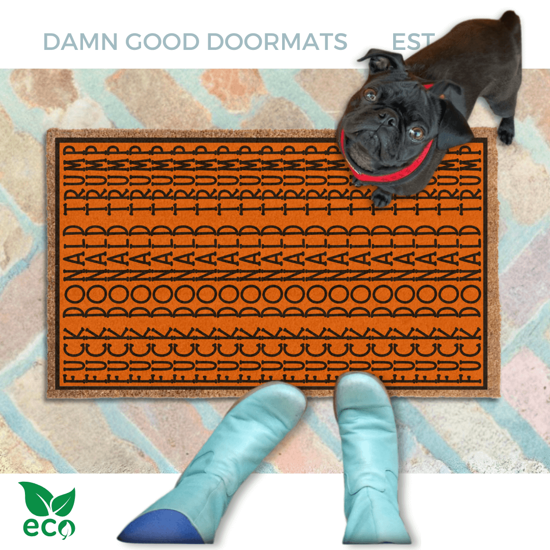 subtle fuck donald trump doormat in abstract contemporary design over a pumpkin orange fall doormat. A pair of feet wearing baby blue boots stands with a black pug dog sitting on the floor next to them. 