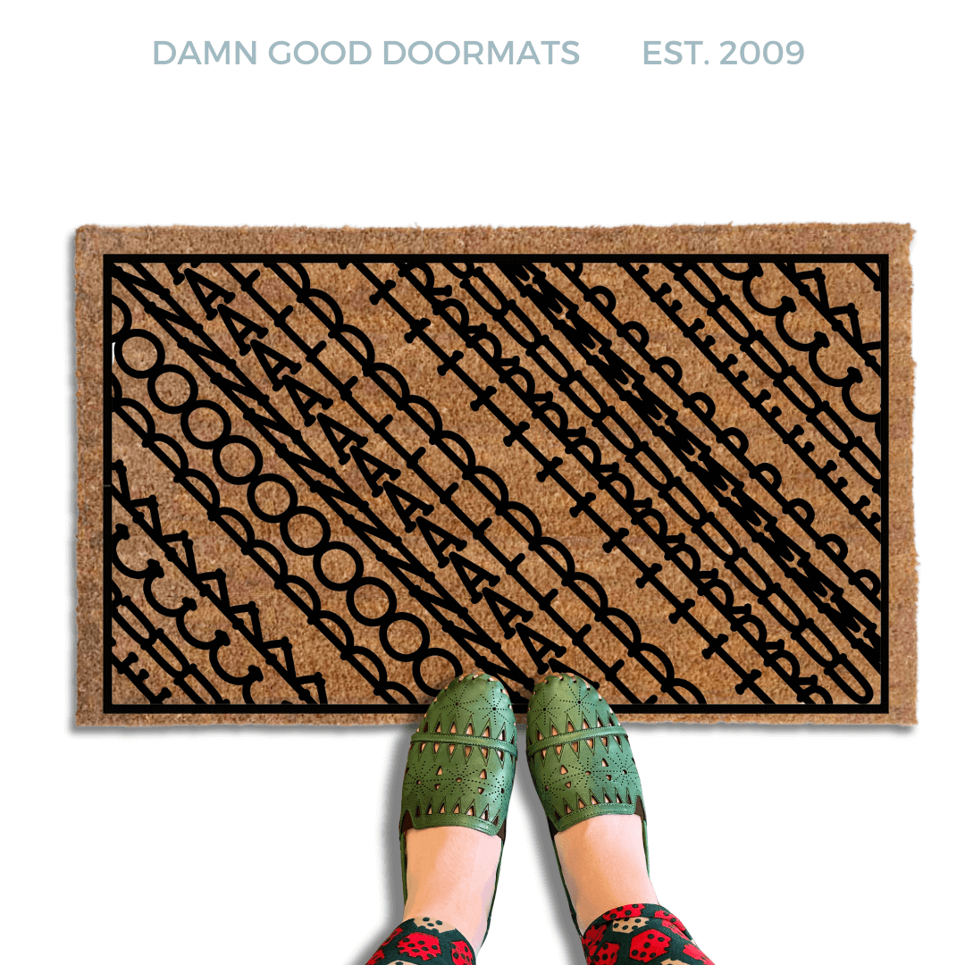 A pair of feet wearing green shoes stands on a subtle patterned FDT Fuck Donald Trump doormat