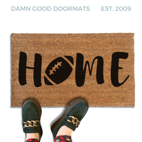 Coir doormat printed with HOME in black brush lettering, with a dark brown football with white laces standing in for the O