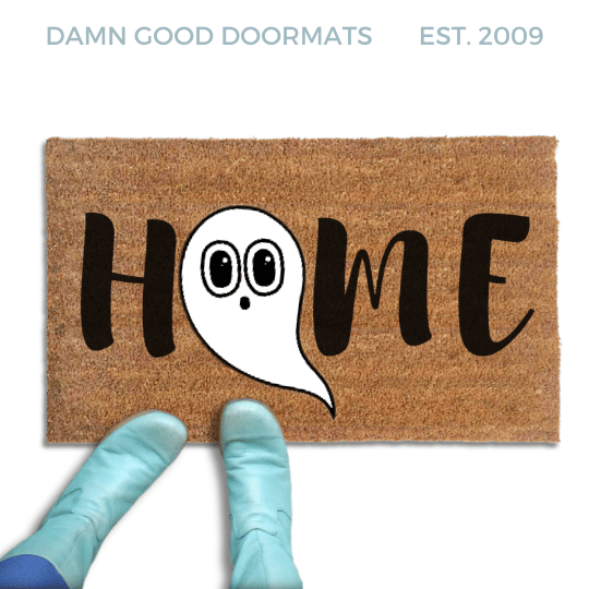 Coir doormat printed with HOME in black brush lettering, with a white cartoon ghost with big round eyes standing in for the O