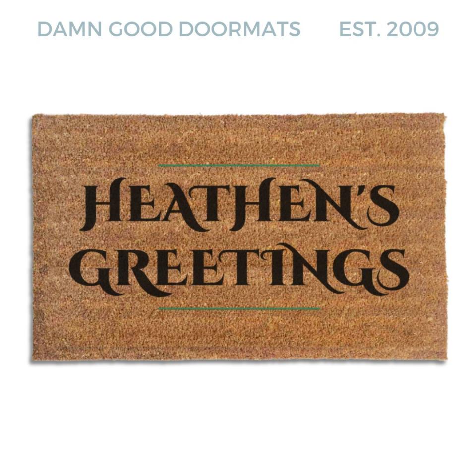 Coir doormat printed with Heathen's Greetings in black engraved capitals between thin green rules