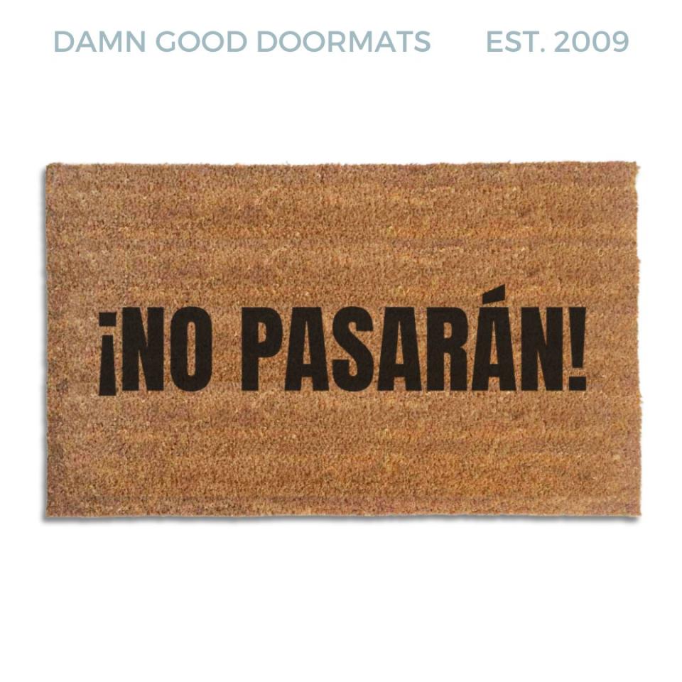 Coir doormat printed with ¡No Pasarán! in tall black condensed capitals