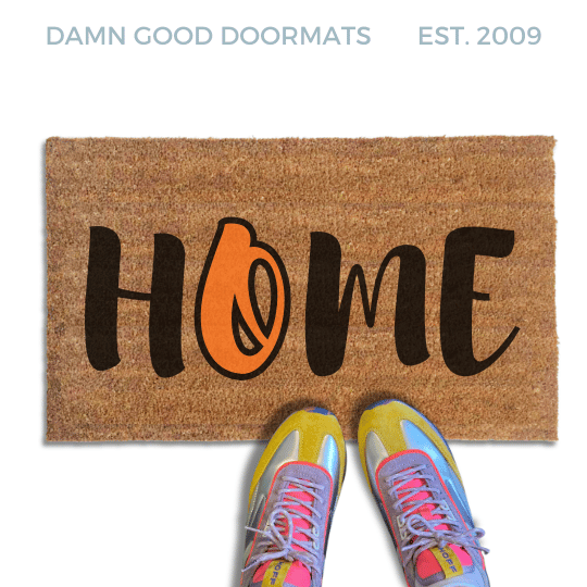 Coir doormat printed with HOME in black brush lettering, with an orange script O for the Baltimore Orioles standing in for the O