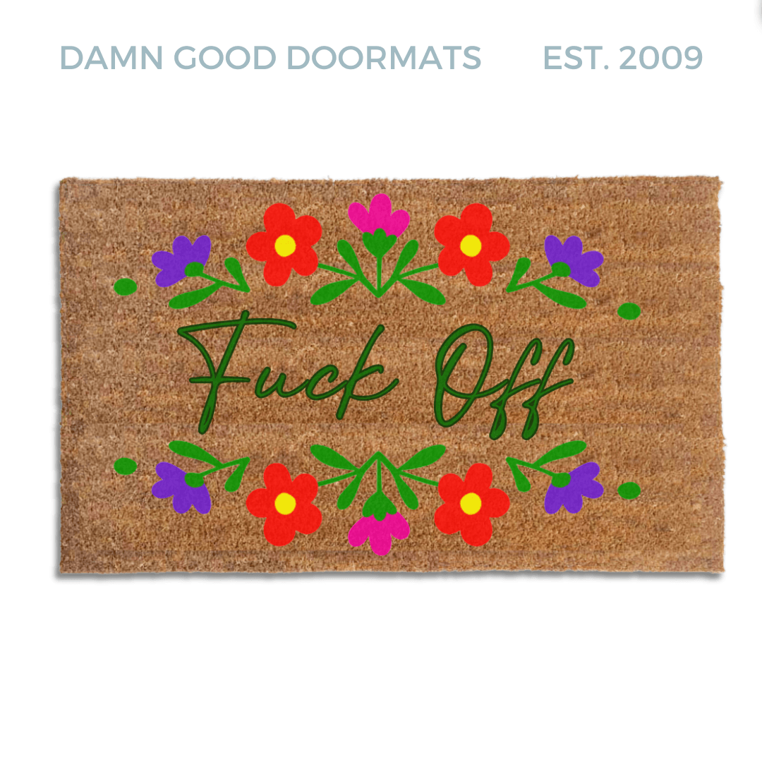 promotional image of a coir doormat reading "fuck off" in cursive with red and purple flowers across the top and bottom