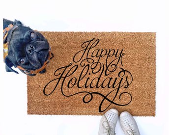 outdoor doormat reading happy holidays in script writing with a black pug puppy