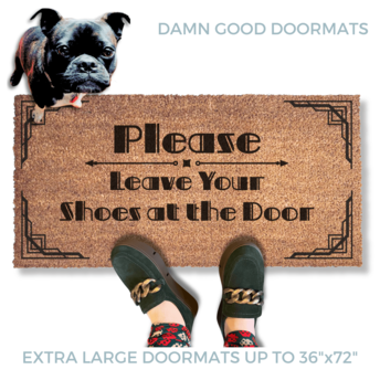 promotional image of a coir doormat reading "Please leave your shoes at the door" . A person in green suede shoes and a black french bulldog  stands on the doormat