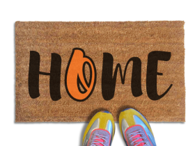 Coir doormat printed with HOME in black brush lettering, with an orange script O for the Baltimore Orioles standing in for the O