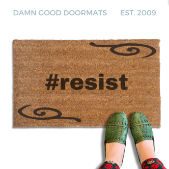 coir doormat with #resist and a decorative border pictured witha. person in green leather slippers