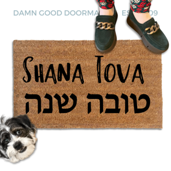 coir doormat reading Shana Tova in english and hebrew with a person in green shoes and a rescue terrier dog
