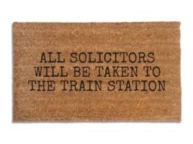 Coir doormat printed with All Solicitors Will Be Taken To The Train Station in black typewriter capitals
