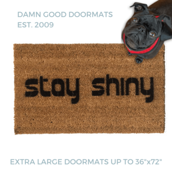 Stay Shiny Firefly themed doormat pictured with a black pug in a red harness looking up