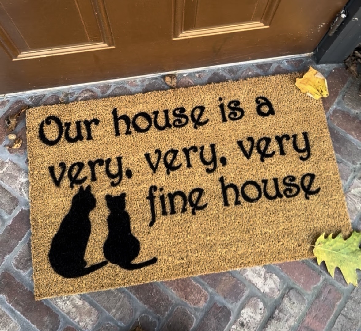 coir fiber doormat reading "our house is a very very very fine house" with two cats on it