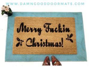 Coir doormat printed with Merry Fuckin Christmas in bold red text, funny holiday welcome mat for a front door.