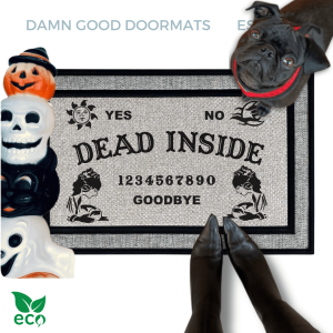 a gray all weather welcome mat with a pug, the word "DEAD INSIDE" on it. The mat has a Ouija board design and the numbers "1234656789" printed on it. The scene includes a person's feet wearing black pointy toed witch boots, a vintage Halloween skull and cat light, and the text "DAMN GOOD DOORMATS EST. 2009" is visible.