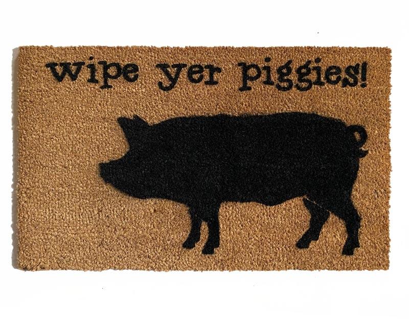 Farmhouse-style doormat with "Wipe Your Piggies" text and pig illustration