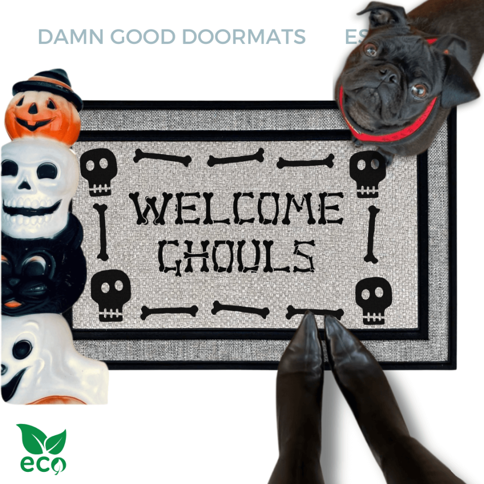a dog standing next to a welcome mat with the text "WELCOME GHOULS" on it. The dog is wearing a collar and appears to be looking at the mat. The mat has a skull design. The image also includes a pair of feet wearing witchy black boots