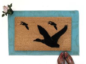Natural coir doormat printed with a V of ducks in flight, flying migration welcome mat at a front door