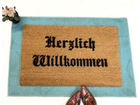 Sustainable coir doormat with 'Herzlich Willkommen' in old-world German lettering, a custom welcome mat for the front door.