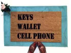 Natural coir doormat with bold black text reading KEYS WALLET CELL PHONE, a sarcastic reminder welcome mat