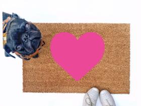 cute pink heart Valentine's Day doormat shown with a little black pug