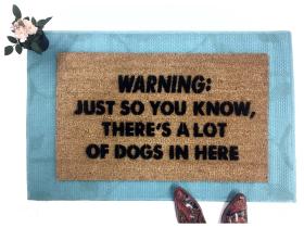 Doormat with warning text reading "DOGS: Just so you know, there's a lot of dogs in here"