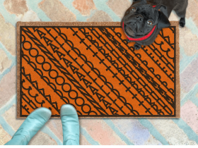 subtle fuck donald trump doormat in abstract contemporary design over a pumpkin orange fall doormat. A pair of feet wearing baby blue boots stands with a black pug dog sitting on the floor next to them. 