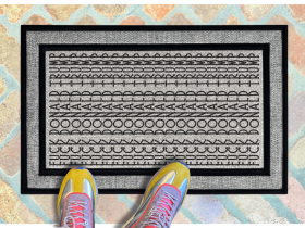 A pair of feet wearing green shoes stands on a subtle patterned FDT Fuck Donald Trump all weather doormat