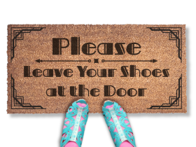 promotional image of a coir doormat reading "Please leave your shoes at the door" . A person in blue cutout sandals and pink tights