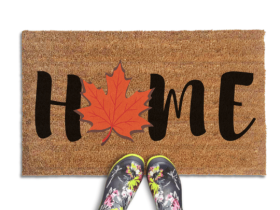 Coir doormat printed with HOME in black brush lettering, with an orange-red maple leaf standing in for the O