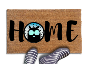 Coir doormat printed with HOME in black brush lettering, with Mothman's dark round silhouette and glowing teal eyes standing in for the O