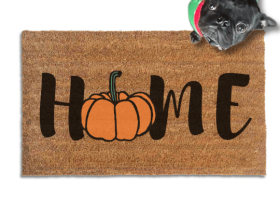 Coir doormat printed with HOME in black brush lettering, with an orange pumpkin standing in for the O